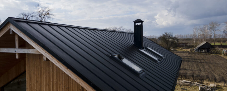 High-angle view of a modern black corrugated insulated roof panel installed on a timber frame residential building