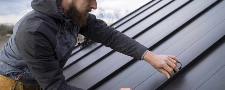 contractor measuring high-density insulated roof panels for a large-scale Brisbane construction project
